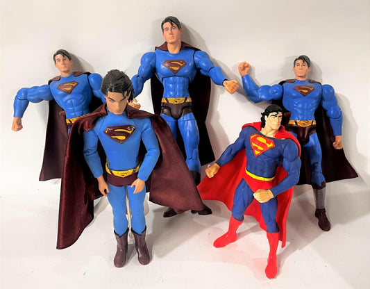 Varias figuras articuladas de Superman alineadas, en distintos tamaños y versiones del traje