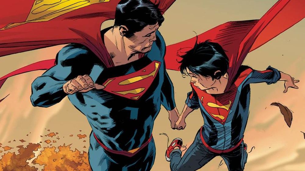 Superman y Jon Kent con traje vuelan juntos sobre un paisaje otoñal
