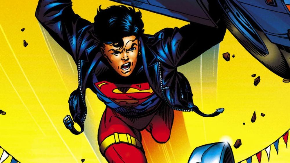 Superboy con cazadora negra, escudo S en el pecho, levanta un coche