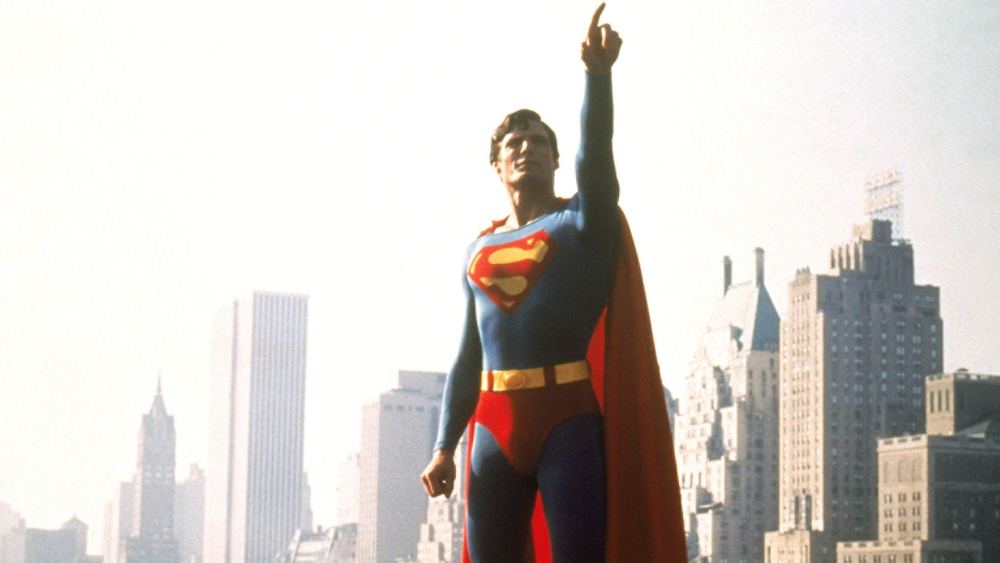 Christopher Reeve como Superman, índice alzado, ante las torres de Metropolis